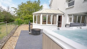 A hot tub, a wooden deck, and a covered patio area. - 4 Bed in Lampeter (oc-41577) (Cellan)
