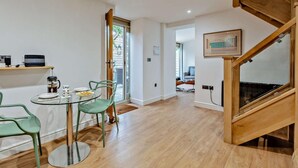 Een modern interieur met een eethoek, een houten trap en uitzicht door een glazen deur.