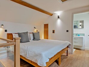 A bedroom with a wooden bed, white bedding, a wooden headboard, a wooden ceiling beam, and a small bedside table. - 1 Bed in Langport (oc-41489) (Curry Rivel)