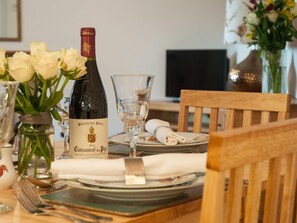 Ein Esstisch, gedeckt mit einer Flasche Blason des Papes Wein, einem Glas und einer Vase mit weißen Blumen.