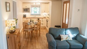 A compact living space with a kitchenette, a dining area, and a sofa. - 2 Bed in Launceston (oc-41992) (Saint Giles on the Heath)
