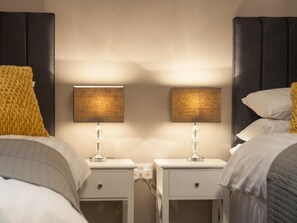 Ein Hotelzimmer mit zwei Nachttischen, jeweils mit Lampe, Schublade und Steckdose.