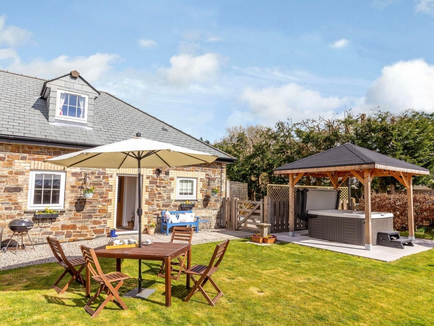A stone house with a patio, outdoor seating, and a barbecue area.