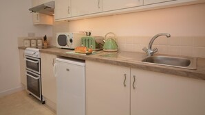 A kitchen with white cabinets, a microwave, a toaster, a kettle, and a sink. - 1 Bed in Par- (oc-42007) (Par)
