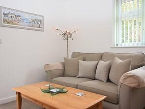 A living room with a beige sofa, a wooden coffee table, and a floor lamp. - 1 Bed in Par- (oc-42007) (Par)