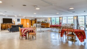 A spacious room with a dining area, a television, and a kitchen area.