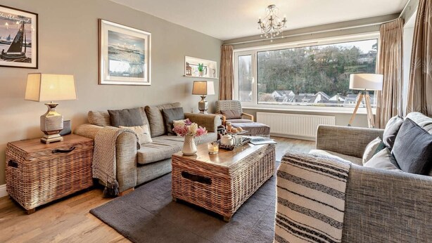A cozy living room with a sofa, armchairs, a coffee table, and a view of the outdoors. - 3 Bed in Ilfracombe (oc-41580) (Combe Martin)