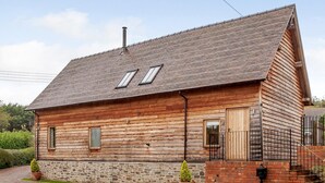 A wooden cabin with a sloped roof, stone foundation, and a small porch. - 3 Bed in Worcester (oc-41983) (Little Green)