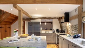 A modern kitchen with a marble island, wooden beams, and a built-in stove. - 3 Bed in Worcester (oc-41983) (Little Green)