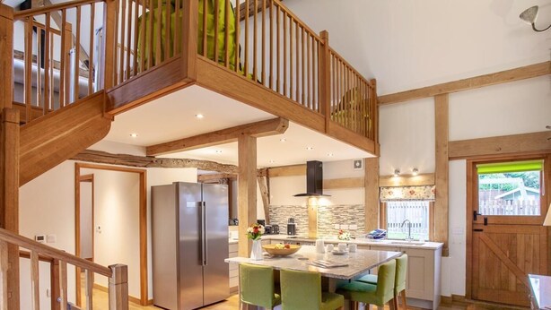 A spacious kitchen with a central island, wooden staircase, and a view of the outdoors. - 3 Bed in Worcester (oc-41983) (Little Green)