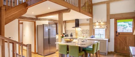 Una cocina amplia con una isla central, una escalera de madera y vistas al exterior.