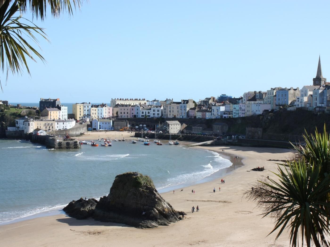 A coastal town with colorful buildings, a sandy beach, and a rocky outcrop.
