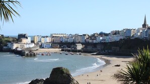 Une ville côtière aux bâtiments aux couleurs vives, dotée d’une plage de sable et d’un promontoire rocheux.