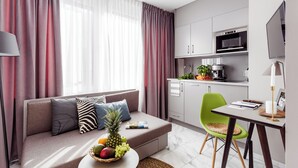 A modern living room with a sofa, a dining table, and a kitchen area with a microwave and coffee maker. - VISIONAPARTMENTS Frankfurt self check-in (Frankfurt am Main)