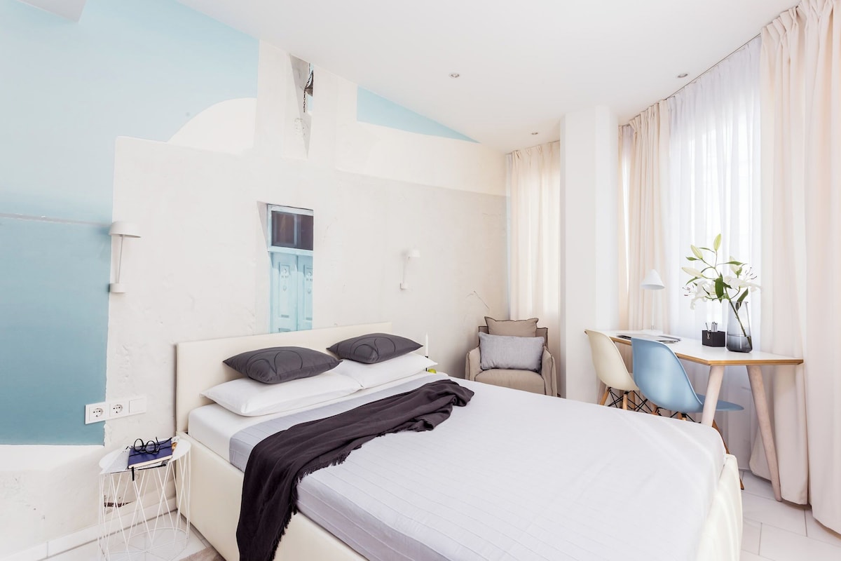 Ein Hotelzimmer mit einem Bett, einem Schreibtisch, einem Stuhl und einem fenster mit Vorhängen.