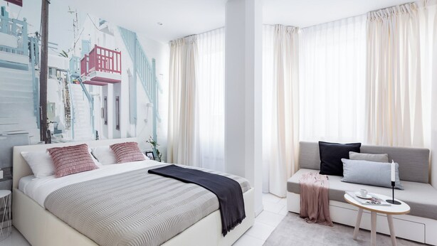 A modern bedroom with a large bed, a sofa, a small table, and a wall with a cityscape mural. - VISIONAPARTMENTS Frankfurt self check-in (Frankfurt am Main)