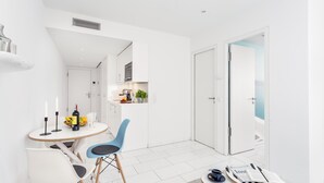 A modern, white interior with a dining area, a kitchen, and a door leading to another room. - VISIONAPARTMENTS Frankfurt self check-in (Frankfurt am Main)