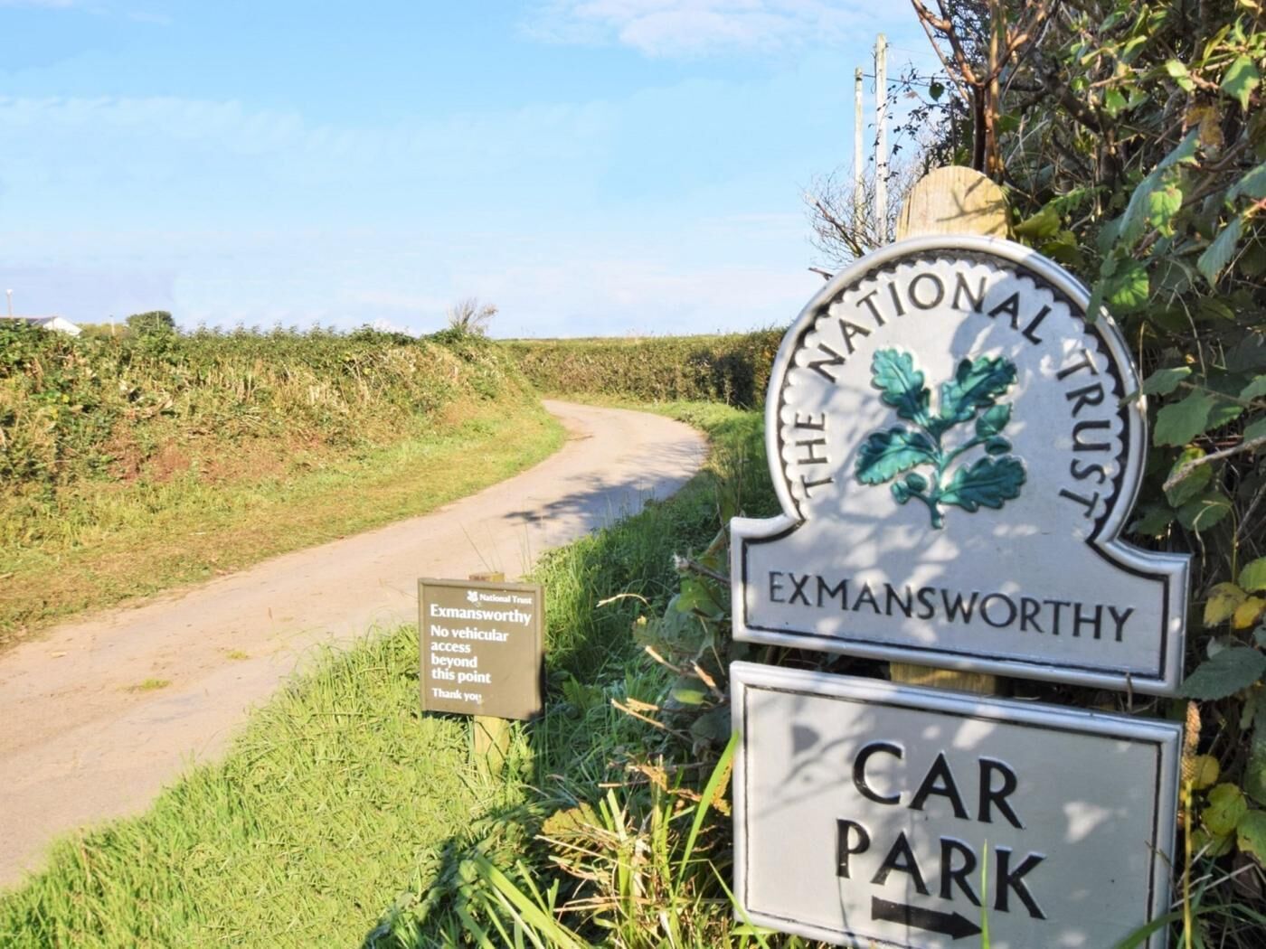 Un panneau indiquant le parking d’Exmansworthy, géré par The National Trust, avec un petit panneau d’information placé en dessous.