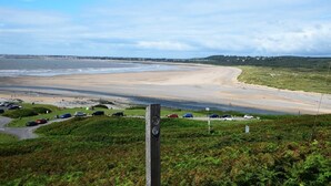 A coastal beach with a parking area and a grassy hill. - 1 Bed in Bridgend (oc-42314) (Bryncethin)