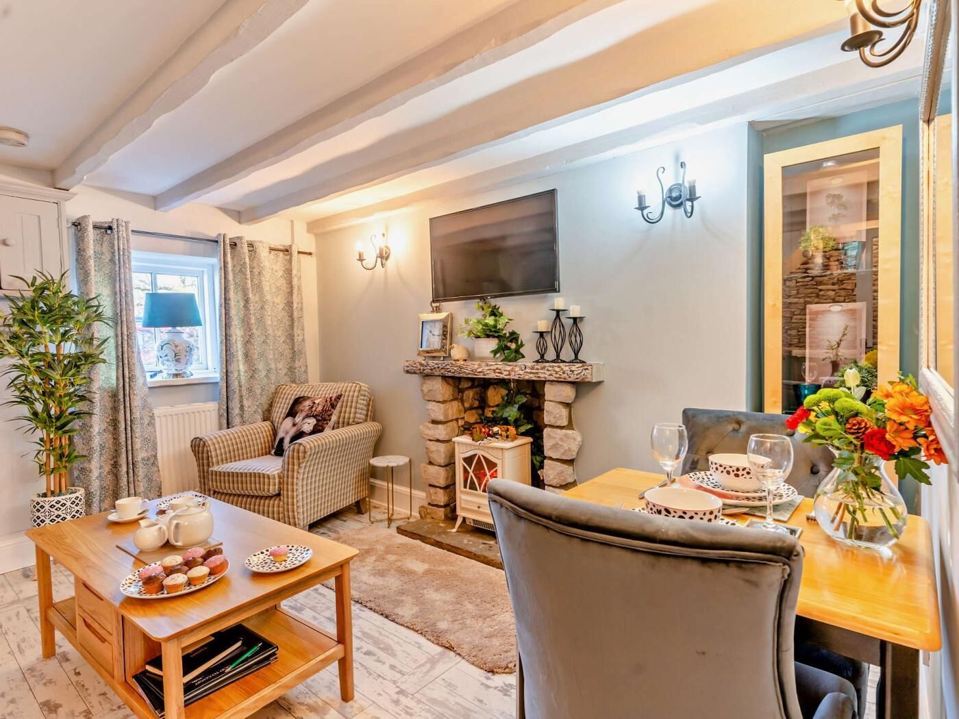 Un salon chaleureux avec une cheminée, un téléviseur fixé au mur et un coin repas avec une table mise pour deux personnes.