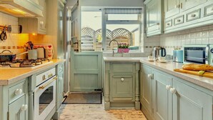 A kitchen with a stove, oven, sink, and a window with a view of a bridge. - 1 Bed in Bridgend (oc-42314) (Bryncethin)