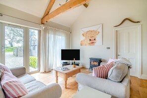 A cozy living room with a sofa, a television, a table with a bottle, and a fireplace. - 2 Bed in Sherborne (oc-41897) (Ryme Intrinseca)