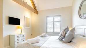 A bedroom with a bed, a bedside table with a lamp, a window, and a mirror. - 2 Bed in Sherborne (oc-41897) (Ryme Intrinseca)