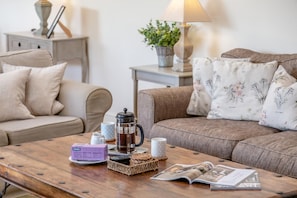 A cozy living room with a wooden coffee table, a sofa, a side table with a lamp, and a potted plant. - 4 Bed in Dorchester (oc-42204) (Sydling Saint Nicholas)