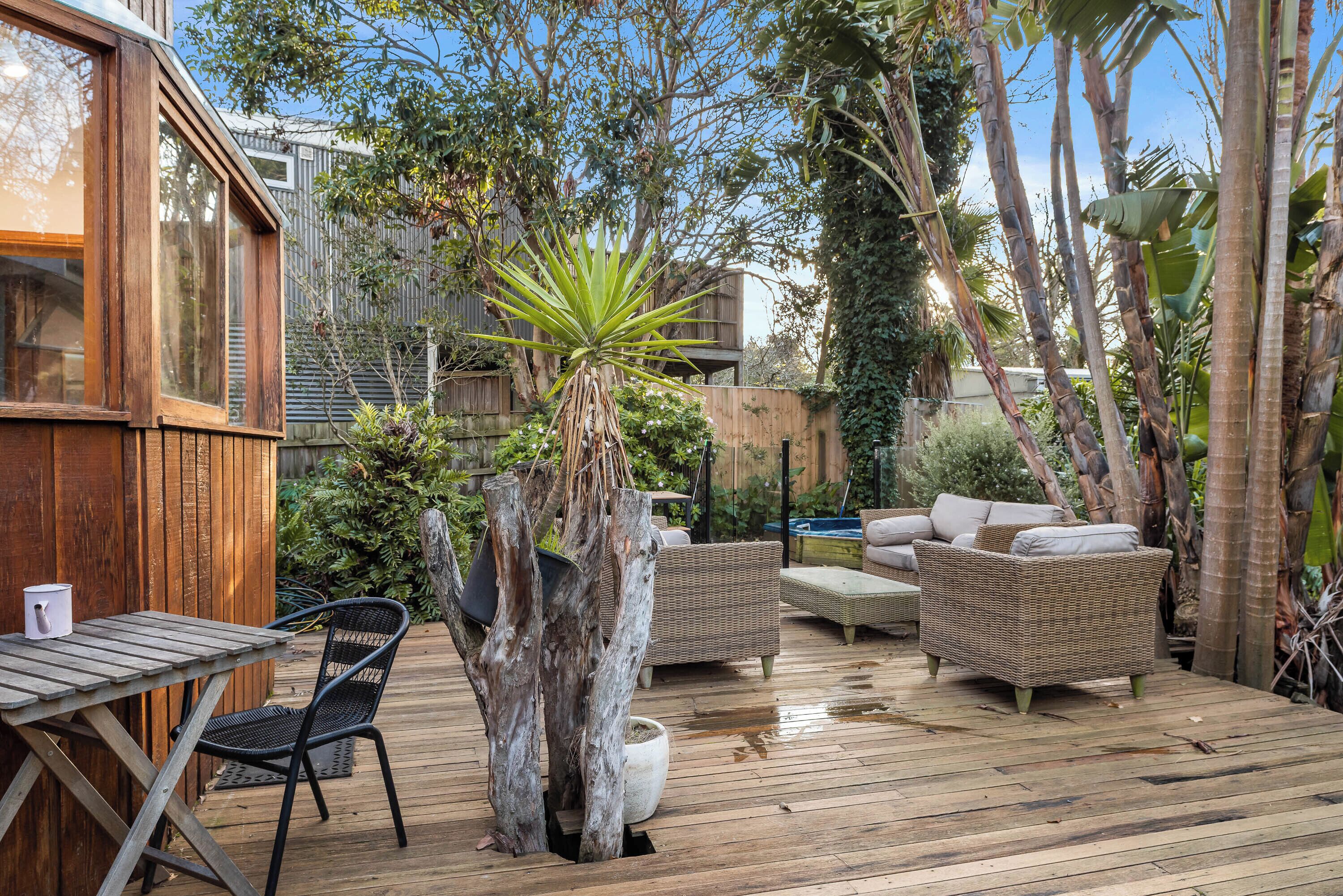 Eine Holzterrasse mit Gartenmöbeln, einem Esstisch und einem Blumentopf.