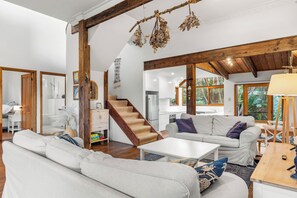 Ein großzügiger Wohnbereich mit Treppe, weißen Sofas und Holzboden.