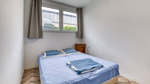 A small bedroom with a bed, a window, and a nightstand.