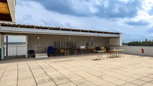 An outdoor patio area with a covered seating area, tables, and chairs.