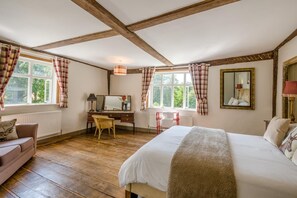 Ein Schlafzimmer mit Bett, Schreibtisch, Stuhl, einem Fenster mit Vorhängen, einer Heizung und einem Spiegel an der Wand.