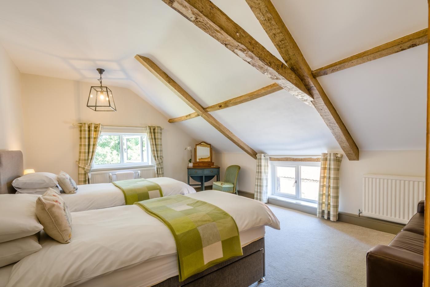 A bedroom with two beds, a window, a radiator, and a wooden ceiling.