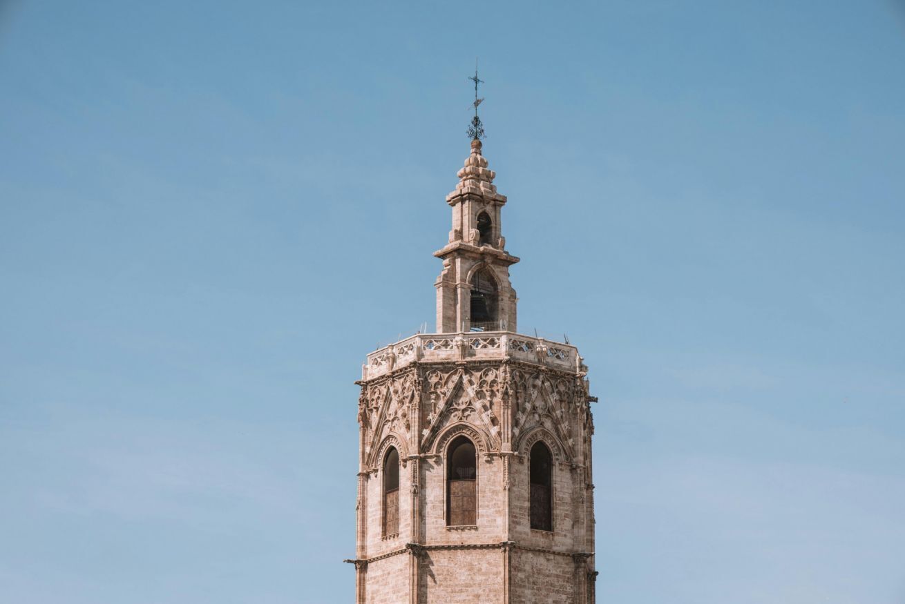 A tower with a cross at the top, arched windows, and intricate stonework.