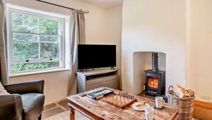 Ein gemütliches Wohnzimmer mit Kamin, Flachbildfernseher, Schachbrett und bequemer Couch.