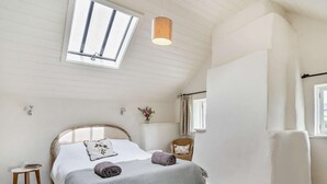 Ein Schlafzimmer mit einem Bett, einem kleinen Tisch, einem Stuhl, einer Lampe und einem Fenster.