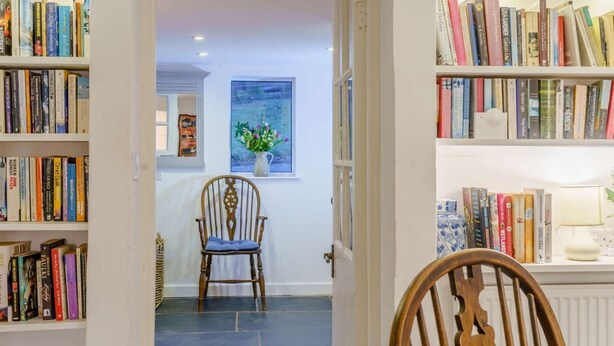 Una habitació amb una estant, una cadira, un quadre i una làmpada.