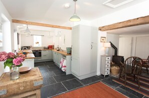 A kitchen with a central island, a dining area with a rustic chair, and a fireplace. - 4 Bed in Monmouth (oc-42868) (Cwmcarvan)