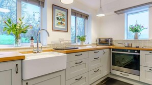 Una cuina moderna amb un rentaplat, fogó i forn, grans finestres i una peça decorativa a la paret.