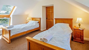 A bedroom with two wooden beds, a skylight, a wooden wardrobe, and a nightstand with a lamp. - 2 Bed in Conwy (oc-42573) (Ty'n-y-groes)