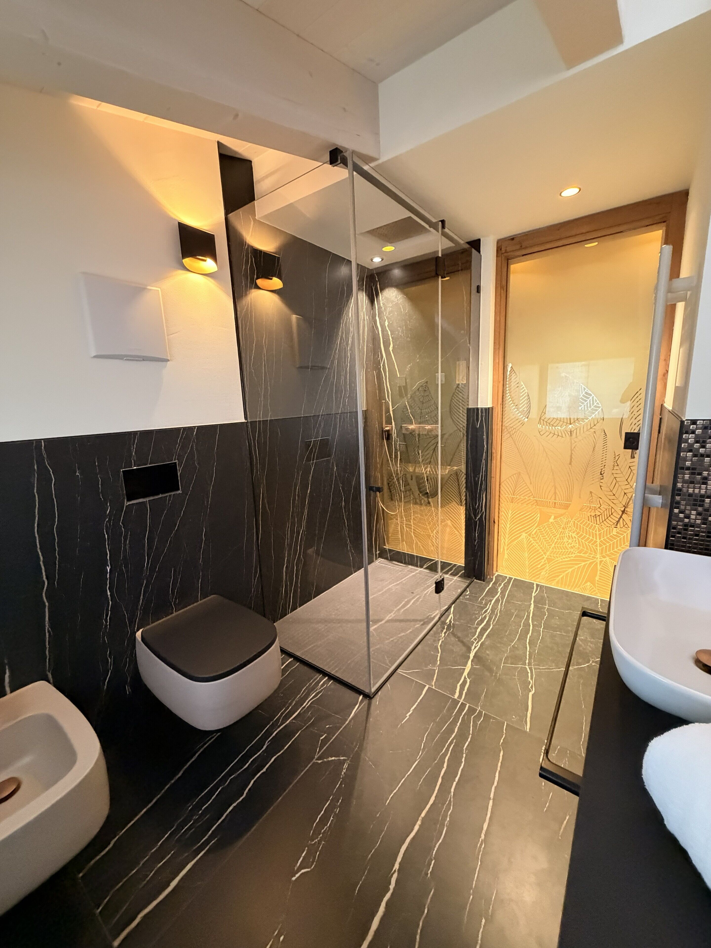 Une salle de bain moderne avec une douche à parois de verre, des toilettes et un lavabo.