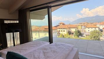 A bedroom with a large bed, a view of a cityscape, and a wooden ceiling.