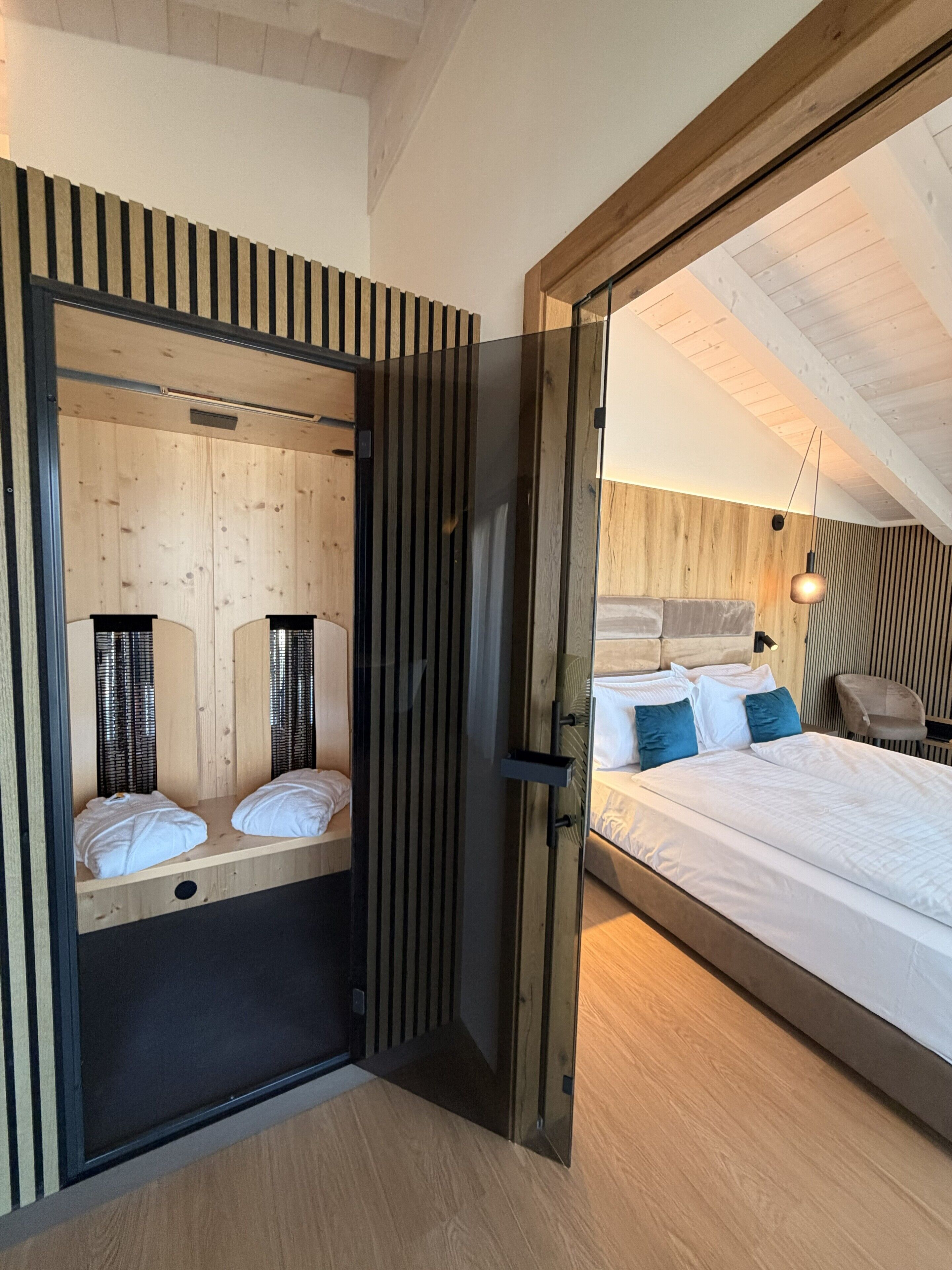 A modern bedroom with a large bed, a wooden ceiling, and a sliding door leading to a smaller room.