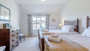 Ein Schlafzimmer mit Bett, Kommode, Stuhl und einem Fenster mit Vorhängen.