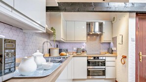 Une cuisine moderne avec des armoires blanches, une cuisinière en acier inoxydable et un plan de travail en bois.