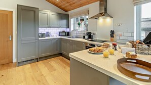 Een moderne keuken met grijze kastjes, een houten plafond en een groot eiland met ontbijtartikelen.
