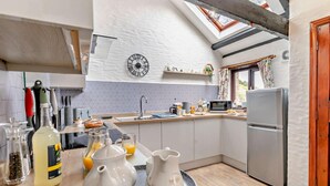 A modern kitchen with a skylight, a clock, and a refrigerator. - 3 Bed in Looe (oc-43128) (Saint Martin-by-Looe)