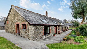 A stone building with a sloped roof, a chimney, and a small porch with chairs. - 3 Bed in Looe (oc-43128) (Saint Martin-by-Looe)