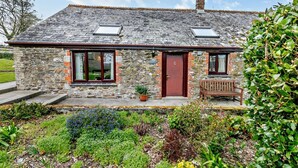 A stone cottage with two skylights, a red door, and a bench outside. - 3 Bed in Looe (oc-43128) (Saint Martin-by-Looe)